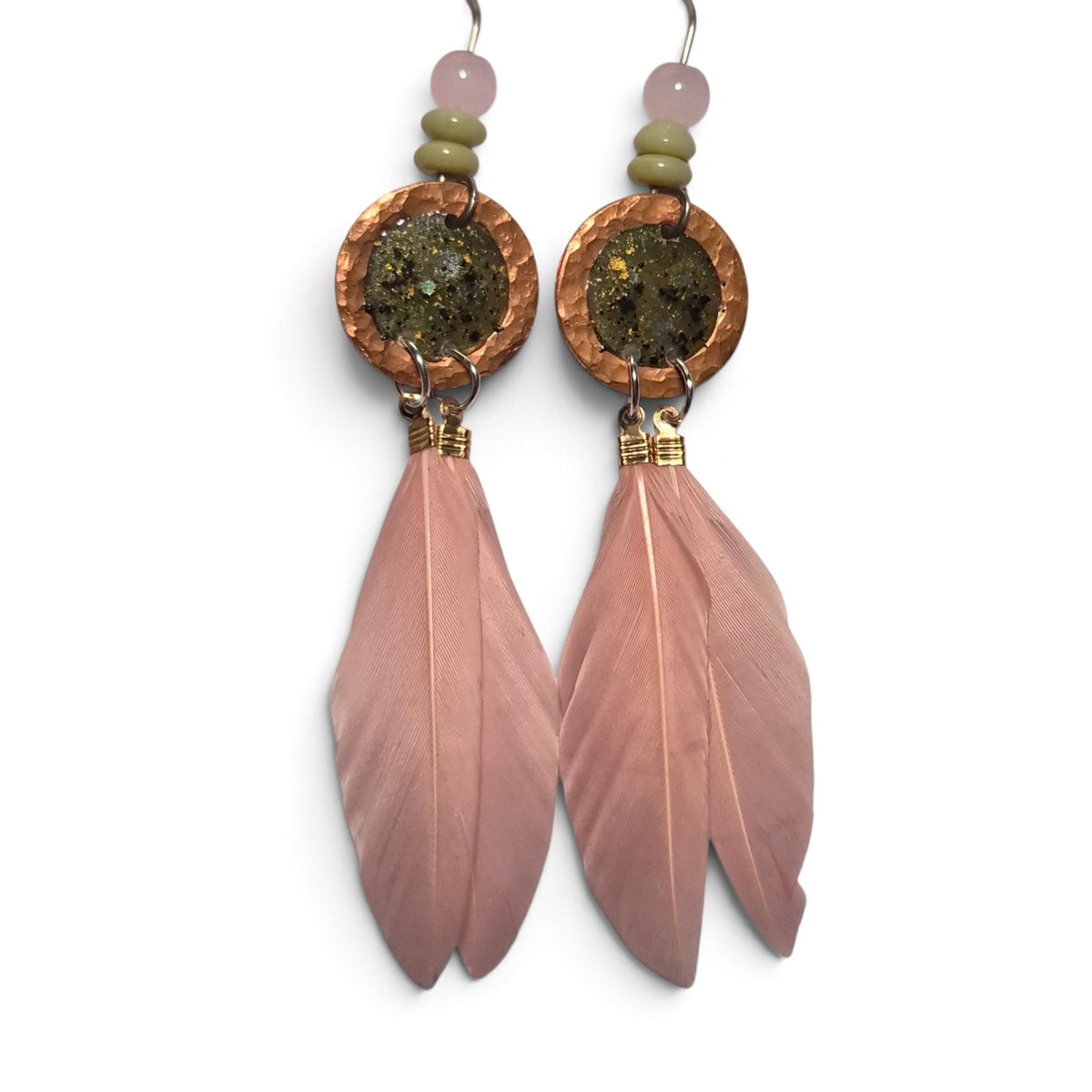 Loergann Studio artisan feather drop earrings with pink feathers, hammered copper discs, and moss-toned stone inlays.